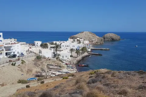 Vista panorámica de la **isleta del Moro, Almería**, con casas blancas, barcas y el mar azul.