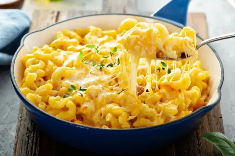 Pyszne, ciągnące się mac n cheese w niebieskiej patelni, z gałązkami tymianku. Idealne na pocieszenie.