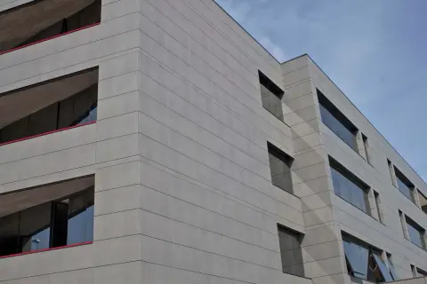 Edificio moderno con fachada de gres porcelánico para fachadas exteriores, líneas horizontales y ventanas oscuras.