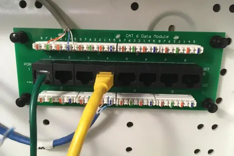 Panel sieciowy Cat 6 z portami RJ45. Widoczne okablowanie i złącza, standard okablowania RJ45 a czy b jest kluczowy dla poprawnego działania sieci.