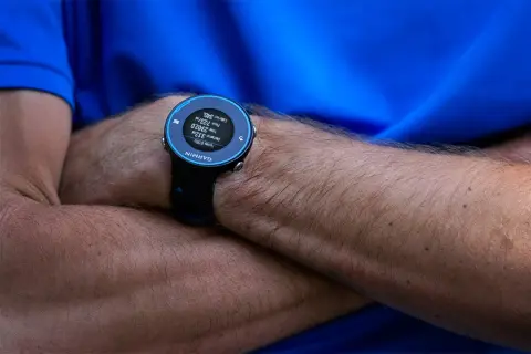 Montre Garmin Forerunner 620 au poignet d'un coureur, affichant distance, temps et calories.