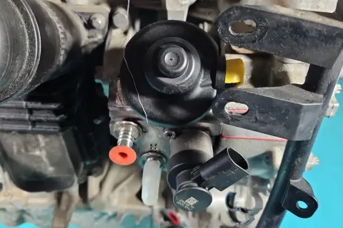 Widok z bliska na elementy silnika, gdzie znajduje się pompa paliwa Toyota RAV4. Widać przewody i złącza.