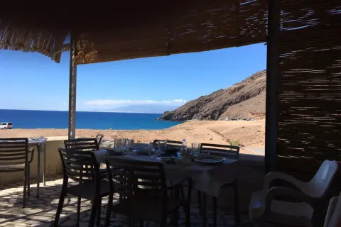 Mesas puestas en restaurantes en La Fabriquilla, Cabo de Gata, con vistas al mar y a la montaña.