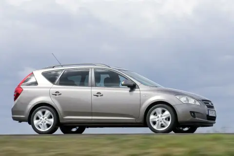 Srebrny Kia Ceed 1.6 benzyna w wersji kombi jedzie po drodze, za nim rozmyte zielone pola.