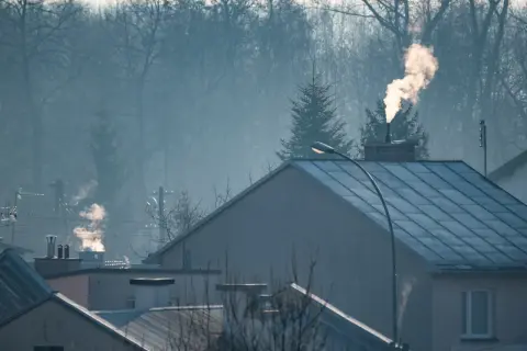 Dym z komina nad domami, czy spaliny z pieca gazowego są szkodliwe? Mglisty poranek nad miastem.