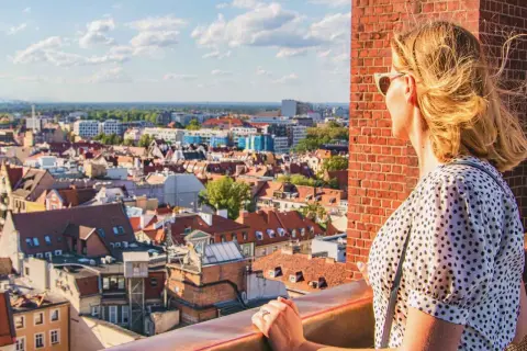 Kobieta podziwia panoramę Wrocławia, planując, co zobaczyć w 1 dzień. Widok na dachy kamienic i niebo.