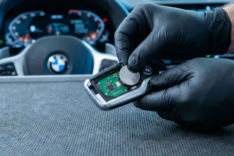 Rękawiczki ochronne ułatwiają wymianę baterii w kluczyku BMW. Widać deskę rozdzielczą i kierownicę.