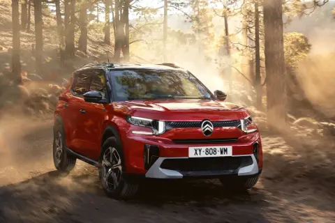 Röd Citroën C3 Aircross testkörs på en dammig skogsväg i solnedgången.