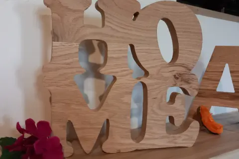 Grosse lettre en bois formant le mot "HOME", décorée de fleurs et d'une petite décoration orange.