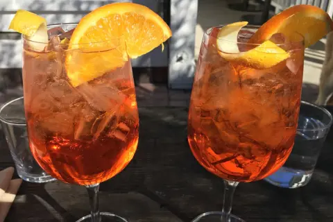 Dwa orzeźwiające aperitif z pomarańczą i skórką cytryny, idealne na letnie popołudnie.