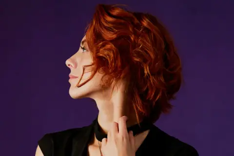 Mujer de 40 con cabello rizado y pelirrojo, un corte moderno y favorecedor.