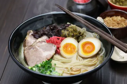 Parujący ramen z grubym makaronem, plastrami wieprzowiny, jajkiem na pół i szczypiorkiem. Idealny wybór, jaki makaron do ramen!