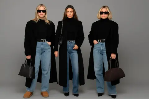 Trzy kobiety prezentują stylowe stylizacje z jeansami, czarne płaszcze i torebki.