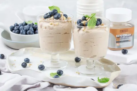 Dwa pucharki z kremowym, szybkim deserem z mascarpone keto, udekorowane borówkami i miętą.