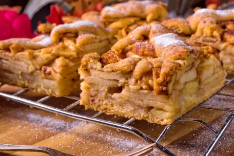 Pyszna szarlotka z jabłkami, idealna do pieczenia na termoobiegu. Posypana cukrem pudrem, czeka na widelce.