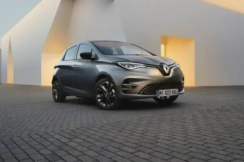 Une Renault Zoe grise, symbole de la mobilité électrique et de son autonomie, se gare devant une architecture moderne aux lignes épurées.