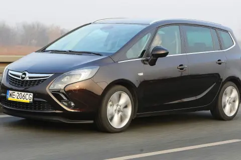 Ciemnobrązowy Opel Zafira Tourer 1.4 Turbo na drodze. Kierowca za kierownicą.