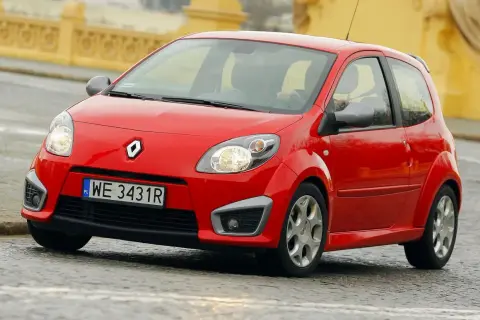 Czerwone Twingo RS na mokrej nawierzchni, z widocznym kierowcą za kierownicą.
