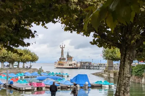 Bunte Tretboote liegen am Steg, im Hintergrund die Imperia-Statue und ein Dampfer am St. Galler See.