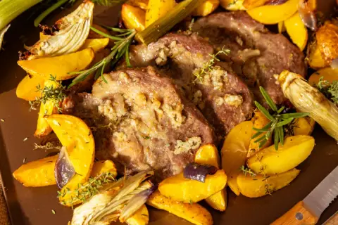 Saftiges Schweinesteak im Backofen ohne Anbraten, umgeben von goldbraunen Kartoffelspalten, Fenchel und Kräutern.