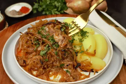 Zwiebelfleisch nach Omas Art: Zartes Fleisch mit karamellisierten Zwiebeln und Salzkartoffeln, garniert mit Petersilie. Ein Klassiker, der immer schmeckt.
