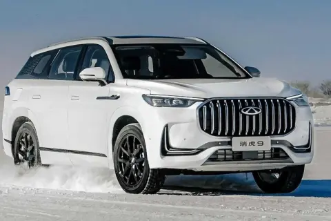 Biały Tiggo 9 pokonuje śnieżne tereny, prezentując swój imponujący grill i elegancką sylwetkę.