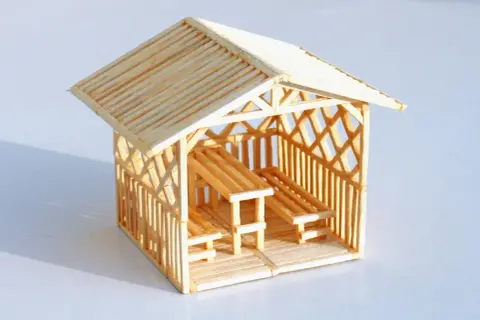 Miniaturowy domek z zapałek z ławkami i stołem. Inspiracja, jak zrobić domek z zapałek.