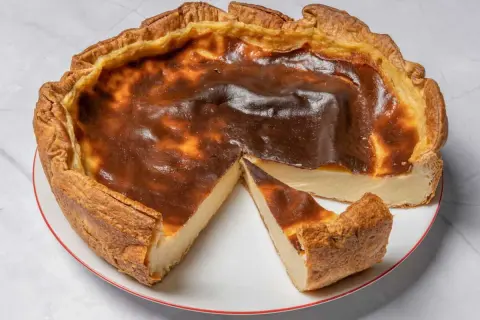 Une délicieuse tarte au flan, dorée et légèrement caramélisée, avec une part coupée pour révéler sa texture crémeuse.