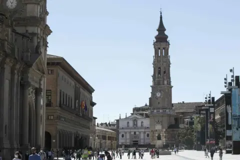 Plaza del Pilar en Zaragoza, con la imponente iglesia de la Seo y el Ayuntamiento. Gente paseando bajo el sol.