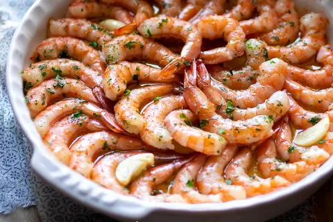 Gamberoni al forno succulenti, conditi con aglio e prezzemolo, pronti per essere gustati.