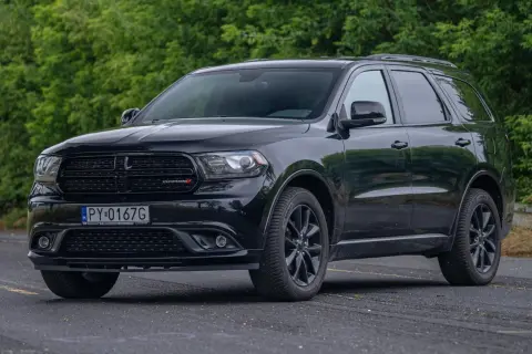 Czarny Dodge Durango 5.7 Hemi z polskimi tablicami rejestracyjnymi stoi na tle zieleni.