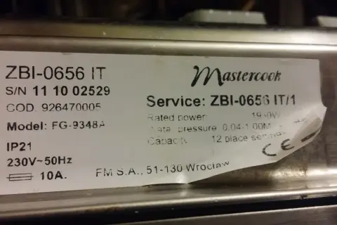 Naklejka z danymi technicznymi kuchenki Mastercook ZBI-0656 IT. Znajdziesz tu m.in. numer seryjny, model FG-9348A, moc 1950W, ciśnienie wody 0.04-1.00M, pojemność 12 kompletów.