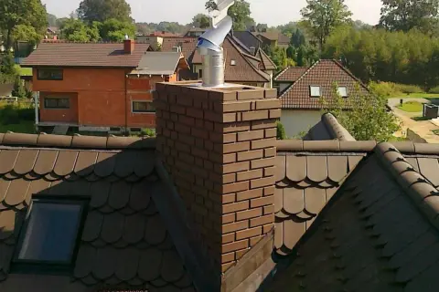 Metalowy daszek na kominie, chroniący przed deszczem. Pokazuje, jak zrobić daszek na komin, by był skuteczny.