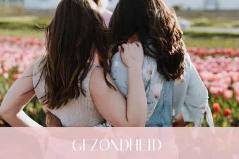Twee vriendinnen omhelzen elkaar in een bloemenveld. Een warme omhelzing die de kracht van hsp en vriendschap symboliseert.