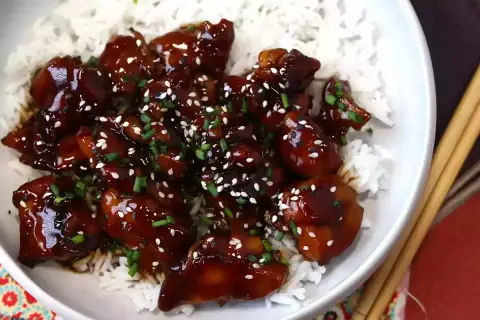 Kyckling i glansig teriyakisås med sesamfrön och gräslök, serverad över ris. Ett enkelt teriyakisås recept att prova.