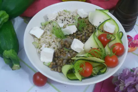 Salade de lentilles, riz, courgettes en rubans, tomates cerises et cubes de feta. Une assiette colorée et saine.
