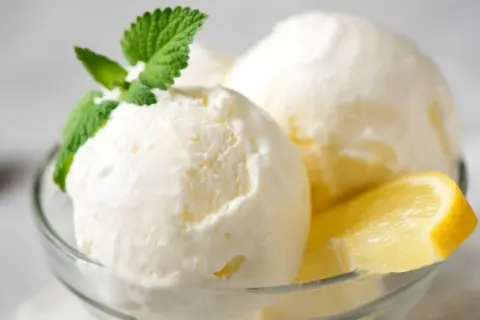 Delicioso helado casero de limón, servido en copa con menta y rodaja de limón. ¡Perfecto para aprender como hacer helado casero!