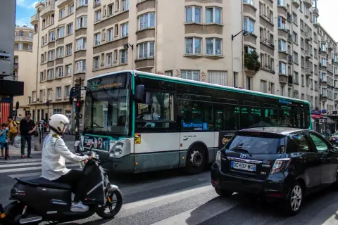 Paryż: autobus miejski i skuter na ulicy, symbolizujące dojazd do centrum z lotniska Charles de Gaulle.