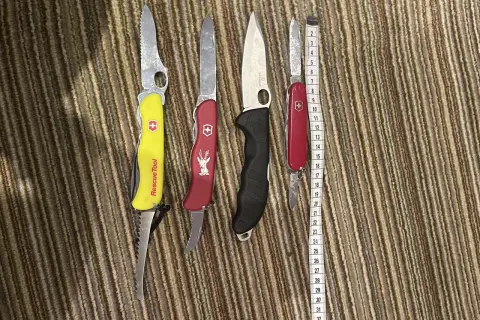 Cztery scyzoryki, w tym jeden z napisem "Rescue Tool", leżą obok miarki. Czy można przewozić nóż w bagażu rejestrowanym?