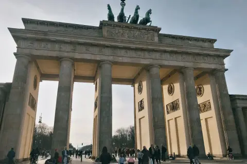 Das Brandenburger Tor, ein Meisterwerk der Klassizismus Architektur, mit seiner Quadriga auf dem Dach. Menschen spazieren davor.