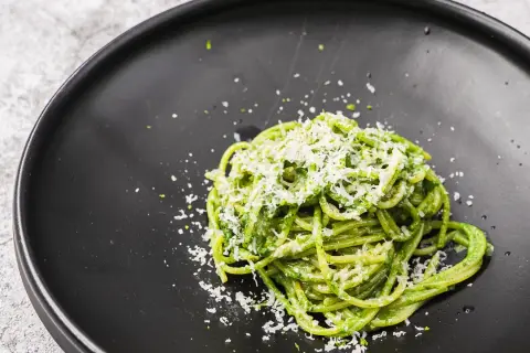 Ein Teller mit leckeren Nudeln mit Pesto, bestreut mit frisch geriebenem Parmesan.
