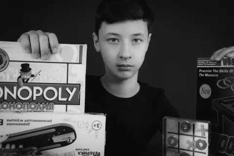 Chłopiec prezentuje gry: Monopoly, kółko i krzyżyk, bilard. Idealna gra dla jednej osoby, by rozwijać umiejętności.