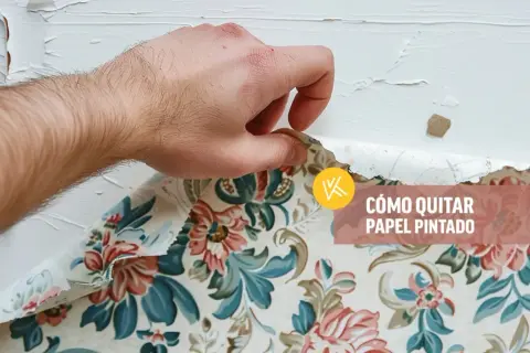 Mano retirando papel pintado floral de una pared blanca.