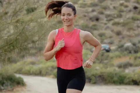 Femme souriante courant en extérieur, prouvant qu'il est possible de progresser en course à pied après 40 ans.