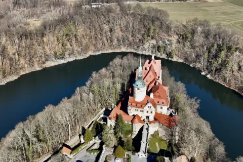 Zamek Czocha, malowniczo położony nad zakolem rzeki, otoczony lasem.