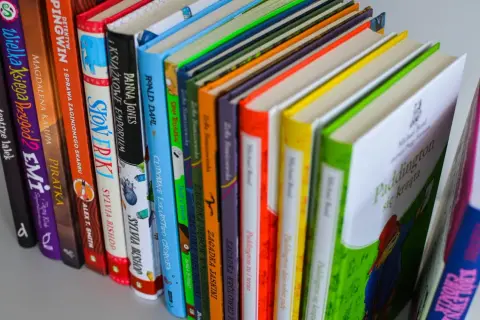 Kolorowe grzbiety książek, w tym "Paddington się krząta", idealne jako książka dla 6 latka chłopca.