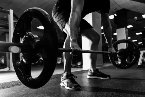 Mężczyzna wykonuje ćwiczenie rack pull, podnosząc ciężar z podłogi.