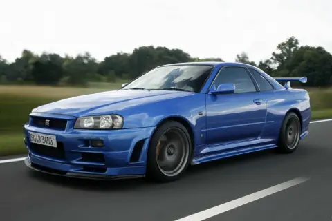 Niebieski Nissan Skyline GT-R R34 w ruchu. Marzenie wielu fanów motoryzacji, a jego cena wciąż rośnie.