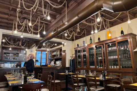 Interno di un ristorante con tavoli apparecchiati e una grande vetrina di vini. Un locale che potrebbe essere tra i migliori ristoranti di Milano per l'atmosfera.