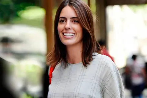 Sofía Palazuelo sonríe con su cabello castaño suelto y un vestido a cuadros.